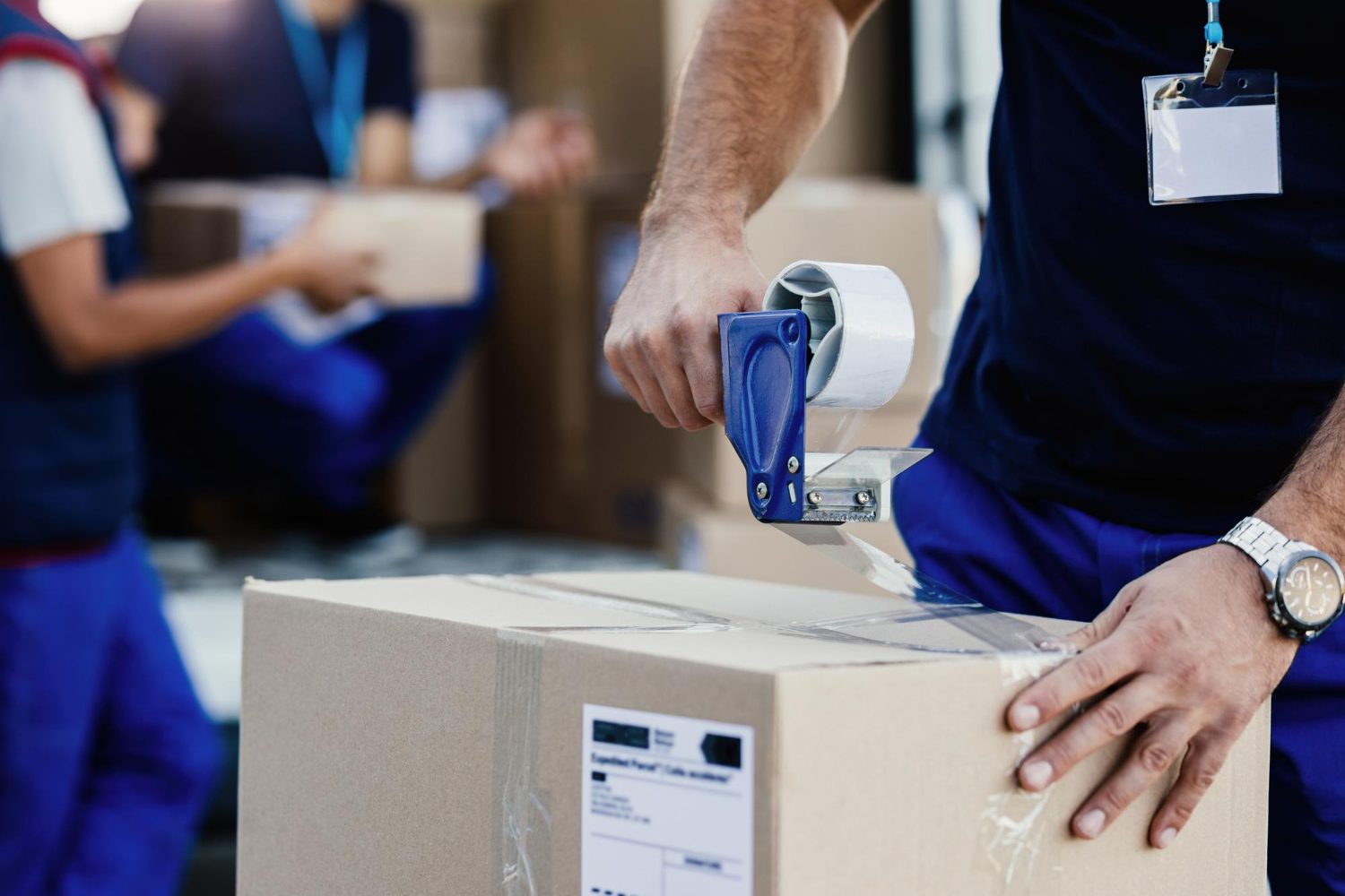 closeup delivery man closing carboard box with tape