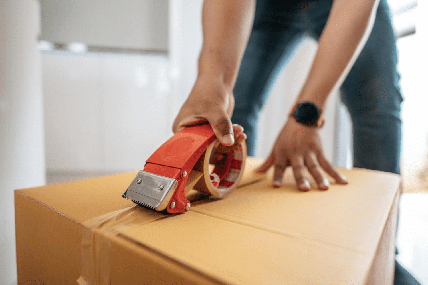 man using glue tape to close cardboard box